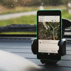 Smartphone with GPS navigation mounted on car dashboard, daylight view.