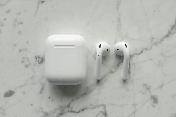 Close-up of modern wireless earbuds and case on a sleek marble surface, showcasing minimalist technology.