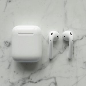 Close-up of modern wireless earbuds and case on a sleek marble surface, showcasing minimalist technology.