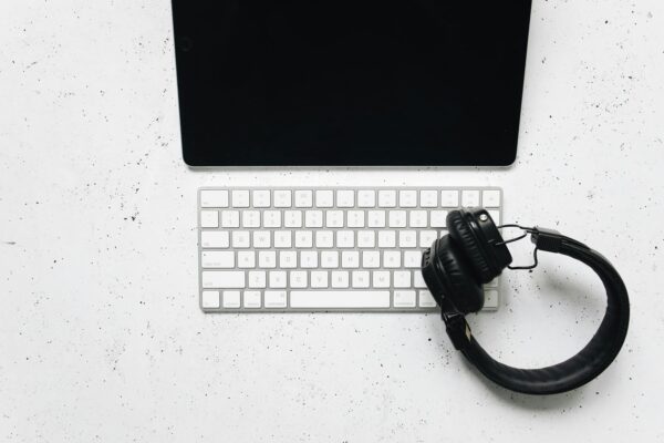Minimalist setup featuring a tablet, keyboard, and headphones on a white desk.