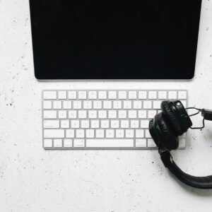 Minimalist setup featuring a tablet, keyboard, and headphones on a white desk.