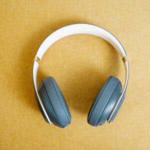 Blue wireless headphones on a yellow background, showcasing modern design and style.